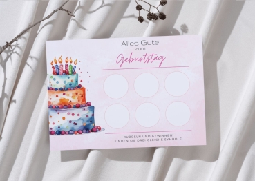 Personalisierbare Rubbelkarte zum Geburtstag mit festlicher Torte in drei Etagen, dekoriert mit bunten Kerzen und Punkten. Die Karte liegt auf hellem Stoff und zeigt sechs unbeschriftete Rubbelfelder auf rosafarbenem Aquarellhintergrund. Perfekt als kreat